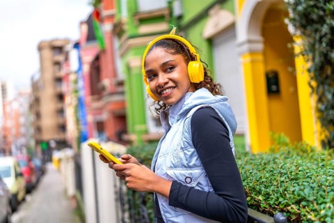 Confident african american woman using phone and listening to music walking next a multicolored