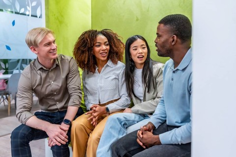 Four colleagues from diverse backgrounds are having a productive discussion in a modern coworking