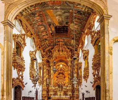 Interior and altar of a historic baroque church richly decorated with gold leaf ornaments and