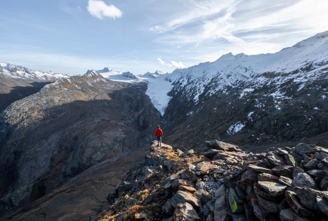 Mountaineer standing on a rock, surrounded by an impressive mountain landscape with snow-covered