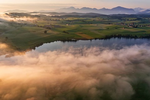 Aerial view of a lake in front of mountains in the morning light, fog, autumn, Riegsee, view of