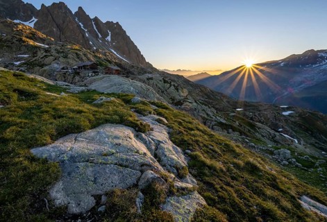 Morning atmosphere with sun star, mountain landscape at sunrise, mountain hut Refuge du Lac Blanc,