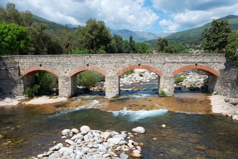 Alte Steinbrücke über einen Fluss in einer gebirgigen Landschaft bei schönem Wetter, Punte Viejo,