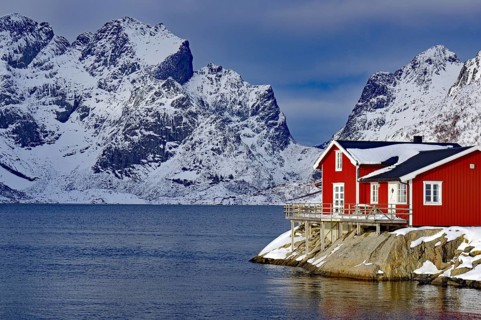 Red house by the fjord in front of snow-covered mountains in a wintry landscape, Scandinavian style