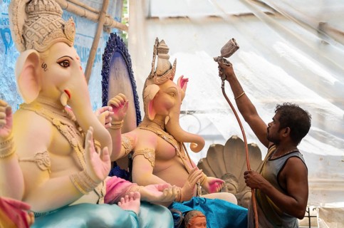 An artisan decorates an idol of the elephant-headed Hindu deity Ganesha at a workshop ahead of the