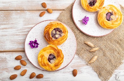 Small cheesecakes with jam and almonds with cup of coffee on a white wooden background and linen