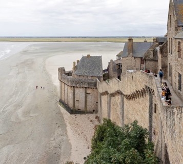 Historic buildings border an extensive sandy beach with views of the sea and the countryside, Le