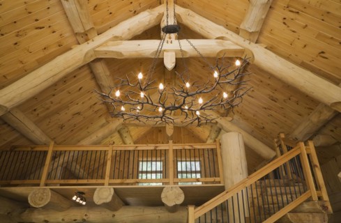 Knotty pine wood planks high cathedral ceiling with illuminated deer antlers chandelier, large