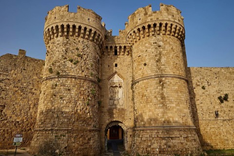 Old-fashioned entrance to a stone castle with tower and entrance gate, sea gate, harbour area,
