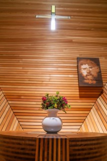 Flower arrangement on an altar table in a modern, wood-panelled interior with cross, Penken,