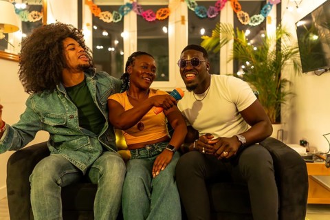Multi-ethnic friends sharing karaoke singing together on the sofa