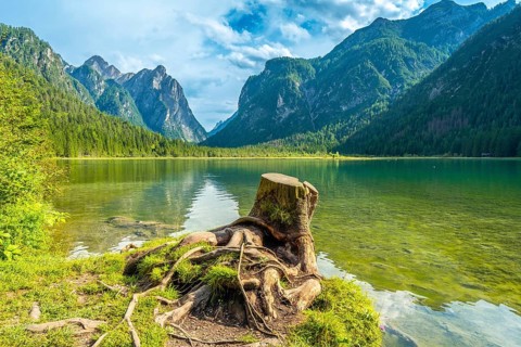 Emerald waters reflecting majestic peaks create a stunning landscape at lake dobbiaco in the