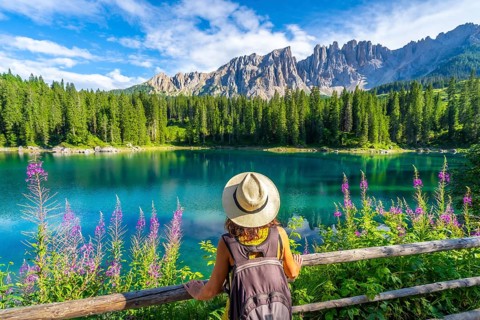Female tourist admiring the stunning turquoise waters of lake carezza with the latemar mountain