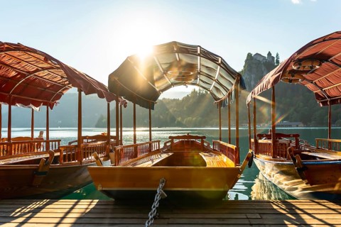Wooden tourist boats moored at dock on lake bled in slovenia with bled island and iconic church in