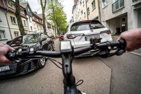 Cycling in the city, city centre street, residential street, 30 km/h zone, traffic with parked cars