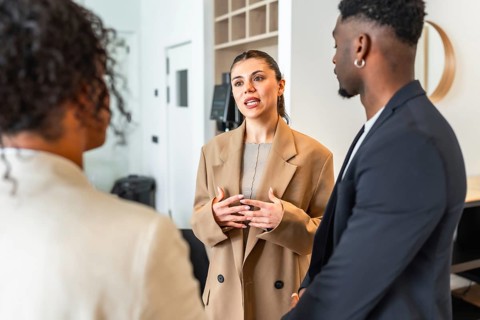 Businesswoman gesturing while speaking to her colleagues during a team meeting in a modern office