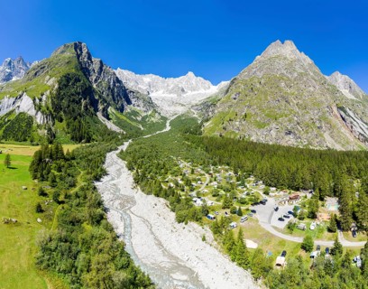 Panoramic aerial view of a campsite at a glacial river, mountain range with glacies in the back, La
