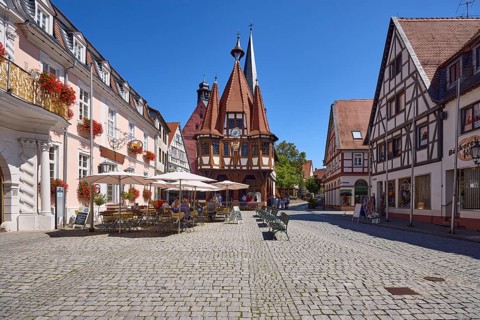 Historic town hall with outdoor area of the confectionery and café Leyhausen under a cloudless blue