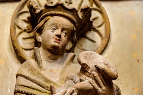 Mother of God with baby Jesus without head, detail of a damaged stone relief of a group of three,