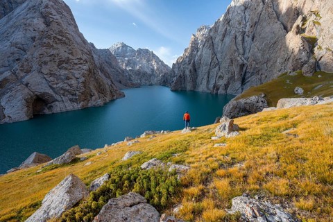 Tourist at the blue mountain lake between rocky steep mountain peaks, Kol Suu Lake, Sary Beles