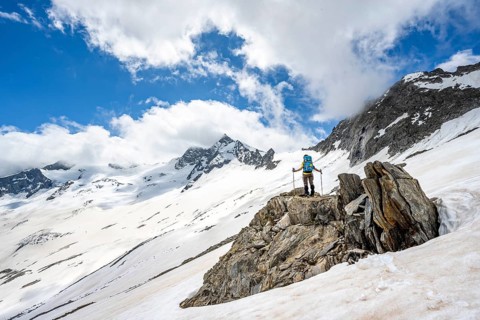 Mountaineer on a rock between snow, descent from the summit of Schönbichler Horn, view of