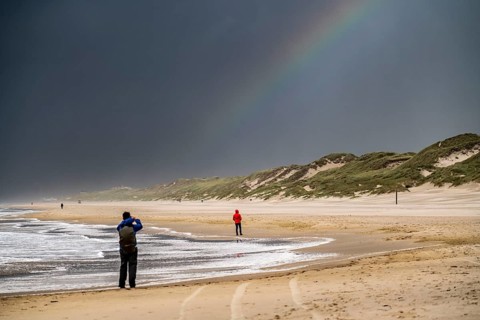 Walkers on the beach, dark storm clouds, choppy sea, autumn on the North Sea in North Holland,