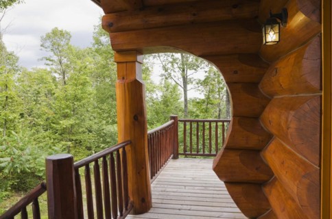 Brown reddish stained Scandinavian log cabin home with with arch and wall made of large chinked