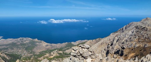 Behind the rocky promontory of the summit of Kali Limni, the bright blue sea of the west side of