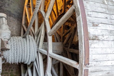 Close-up of a wooden wheel with rope under golden light, Le Mont-Saint-Michel