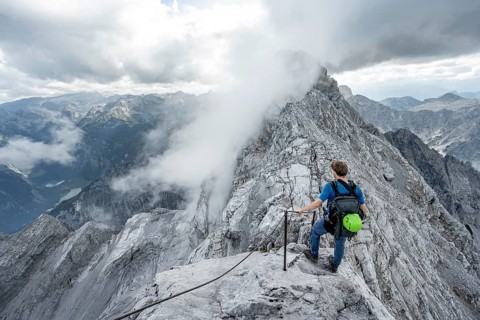 Mountaineer on a narrow rocky ridge on a steel cable, Watzmann crossing to Watzmann Mittelspitze,