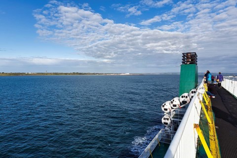 Passengers on a ferry between Ireland and Wales, view of the sea and coastline, spring clouds,