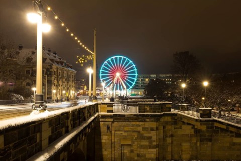 Christmas illumination on the Augustus Bridge in the snow with log cabin, Ferris wheel and steps,