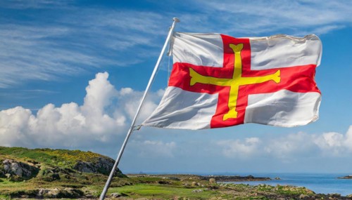 The flag of the Isle of Guernsey, Great Britain, flutters in the wind
