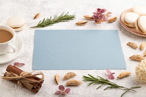 Blue paper sheet mockup with cup of coffee, almonds and macaroons on gray concrete background.