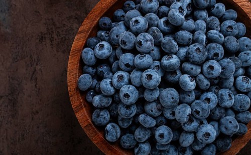 Fresh blueberries, in a wooden bowl, on the table, top view, close-up, no people