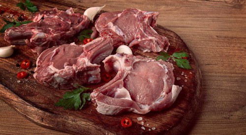 Raw calf meat, meat on the bone, meat for barbecue, cutting board, with spices and herbs, top view