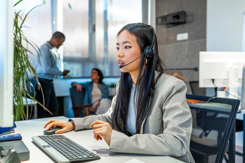 Young asian businesswoman wearing headset working with computer in a modern coworking office,