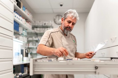 Pharmacist checking medicines on rack. Chemist searching the medicines at storage self