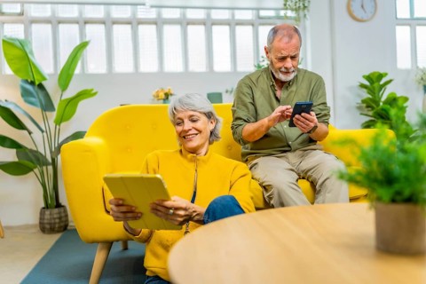 Senior couple using diverse devices and technology together at home