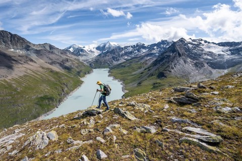 Mountaineer on the summit of Mont de la Blana, view of a blue mountain lake, Lac des Dix reservoir,