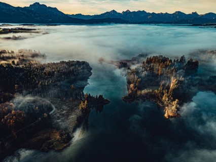 Autumn sunrise in the foothills of the Alps with fog at Illasbergsee and Forggensee near Halblech