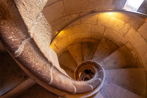 Warm light illuminating ancient stone spiral staircase descending into the depths of barcelona