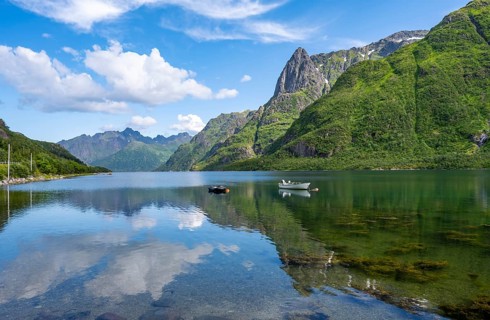 Small boats at the fjord Austnesfjorden, idyllic Norwegian fjord landscape, mountains reflected in
