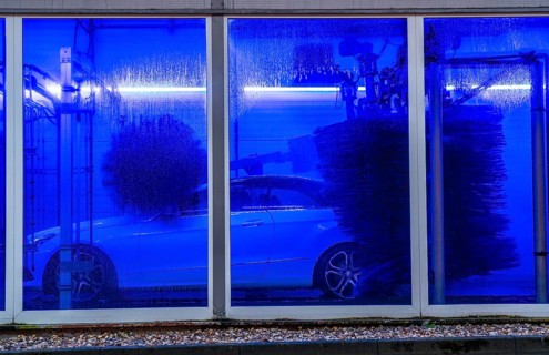 Car in an automatic car wash, car wash tunnel, cleaning foam is sprayed on, rotating brushes clean