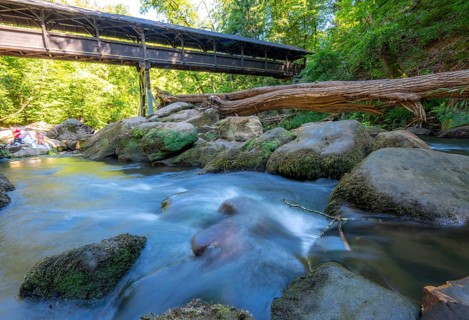 The Irrel Waterfalls, rapids in the lower reaches of the Prüm, covered wooden bridge for hikers,