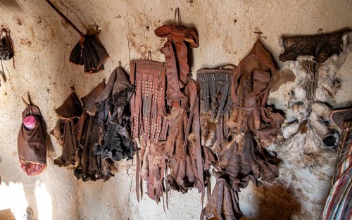 Various traditional leather aprons hanging on the wall, interior of a mud hut of the first woman in
