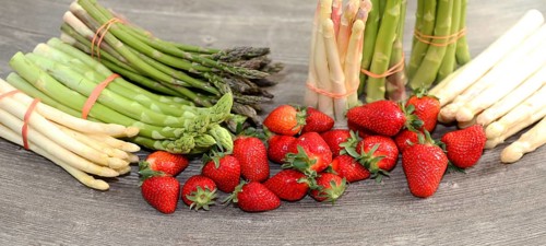 Green asparagus, white asparagus and fresh strawberries decorated on a rustic wooden table