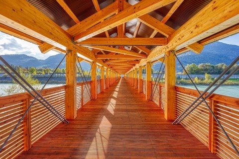 Symmetrical interior view of a wooden bridge with a view of the river and mountains, Inn