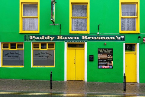 A green-painted pub façade on the roadside, Dingle
