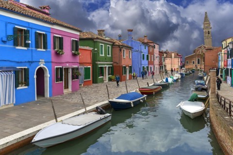 Colourful houses on the canal, behind the leaning tower of the church of St. Martin Vescovo, 16th